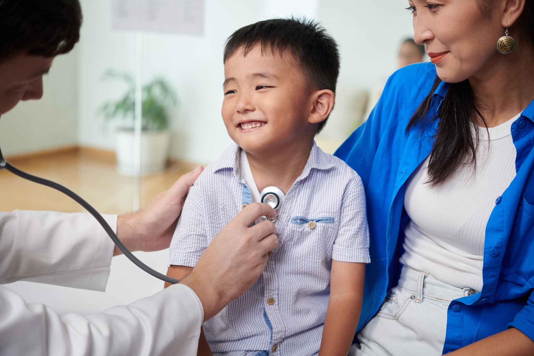 Young boy smiling while he sits next to his mother during a doctor's visit