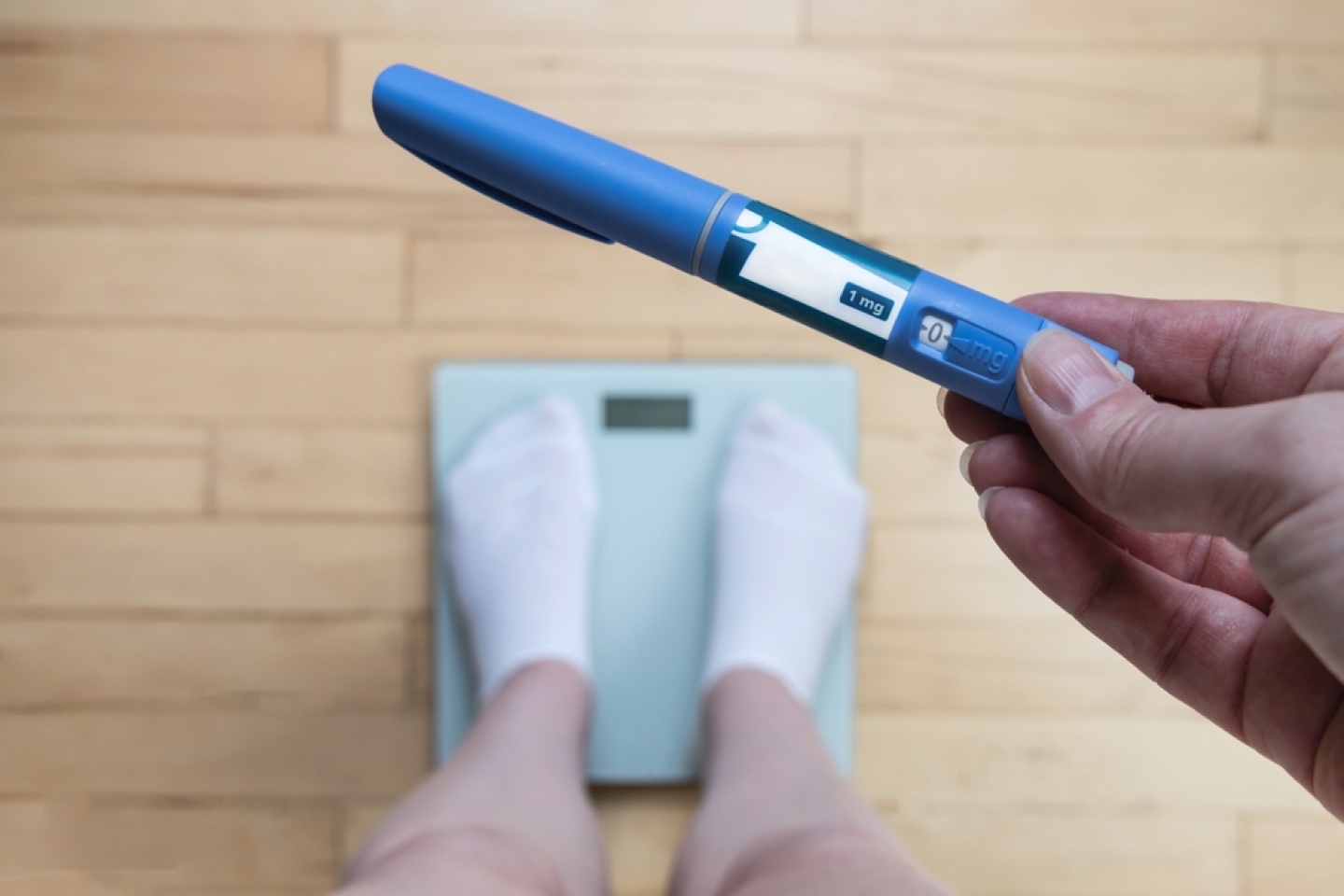 Ozempic Insulin injection pen for diabetics and weight loss. Woman weighs herself and holds Ozempic in her hand. Weight loss concept.